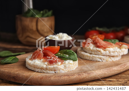 Puffed rice cakes with prosciutto, tomato and basil on wooden board Puffed rice cakes with prosciutto, tomato and basil on wooden board 142431487