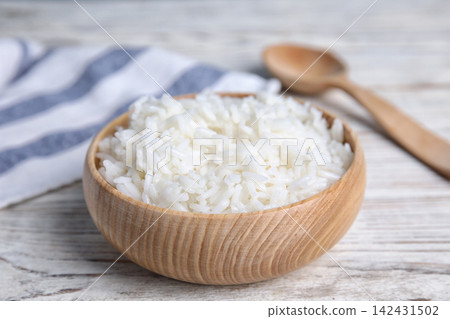 Bowl with tasty cooked rice on white wooden table, closeup Bowl with tasty cooked rice on white wooden table, closeup 142431502