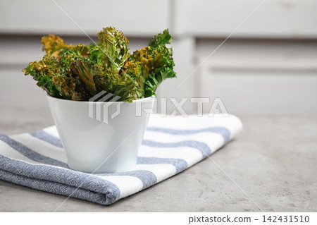 Tasty baked kale chips on grey table. Space for text Tasty baked kale chips on grey table. Space for text 142431510
