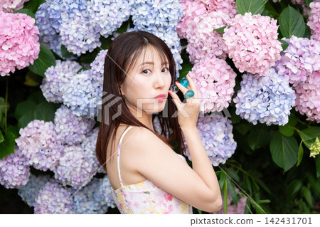 一名女子站在繡球花前擺姿勢,手中拿著玻璃球。 一名女子站在繡球花前擺姿勢,手中拿著玻璃球。 142431701