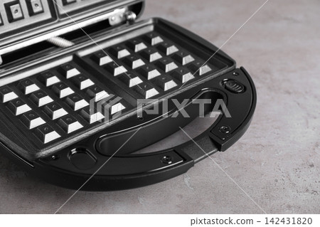 Modern waffle iron on grey stone table, closeup 142431820