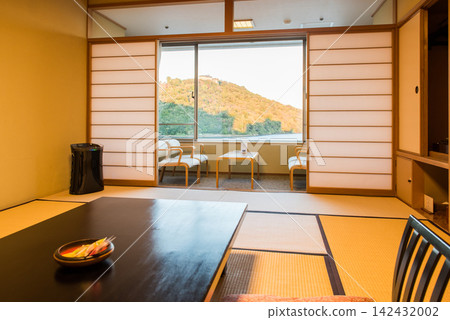 A guest room in a long-established inn; a low table in the foreground, a wide veranda in the background, and a sunset view outside the window. A guest room in a long-established inn; a low table in the foreground, a wide veranda in the background, and a sunset view outside the window. 142432002