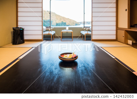 一家歷史悠久的客棧的客房；前景中有一張矮桌，背景中有一條寬敞的陽台，窗外是日落的景色。 142432003