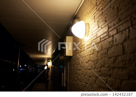 夜晚,溫暖的路燈照亮了磚牆。 夜晚,溫暖的路燈照亮了磚牆。 142432187