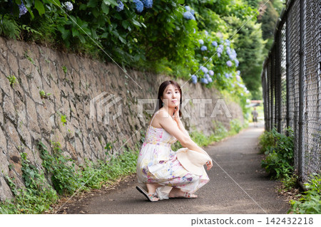 一位年輕女子坐在繡球花街上 一位年輕女子坐在繡球花街上 142432218