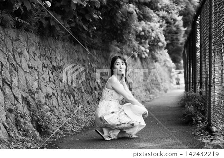 一位年輕女子坐在繡球花街上 一位年輕女子坐在繡球花街上 142432219