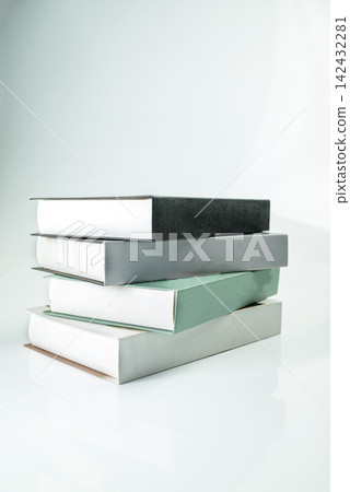 A minimalist stack of four books in muted colors on a reflective light surface. Study or education concept A minimalist stack of four books in muted colors on a reflective light surface. Study or education concept 142432281