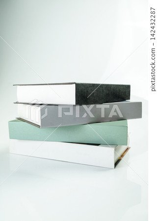 A minimalist stack of four books in muted colors on a reflective light surface. Study or education concept A minimalist stack of four books in muted colors on a reflective light surface. Study or education concept 142432287