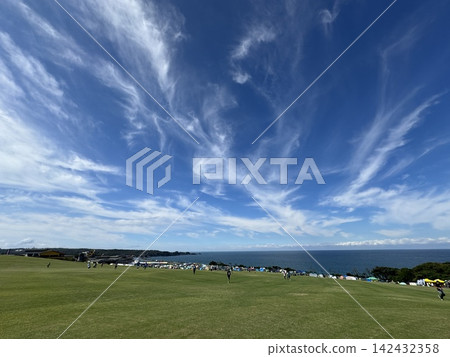 A view of a vast grassy field overlooking the blue sky and the sea. A view of a vast grassy field overlooking the blue sky and the sea. 142432358