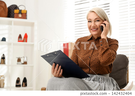 Female business owner talking on phone in boutique 142432404