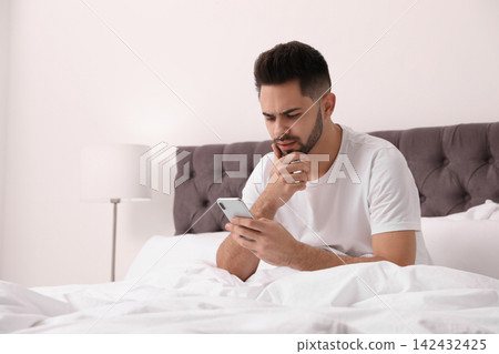 Young man addicted to smartphone in bed at home Young man addicted to smartphone in bed at home 142432425
