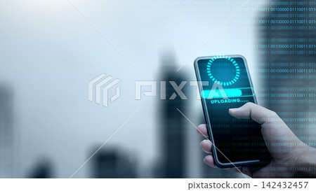 Hand holding a smartphone displaying an uploading progress bar with blue light overlays and binary code. Concept of cloud computing storage and digital storage technology 142432457
