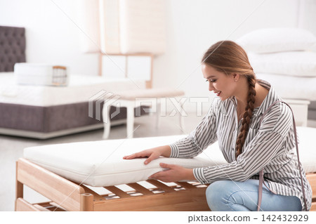 Young woman touching mattress in furniture store. Space for text Young woman touching mattress in furniture store. Space for text 142432929
