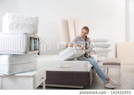 Young woman choosing mattress in furniture store Young woman choosing mattress in furniture store 142432933