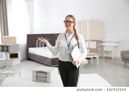 Young saleswoman with clipboard in mattress store Young saleswoman with clipboard in mattress store 142432934