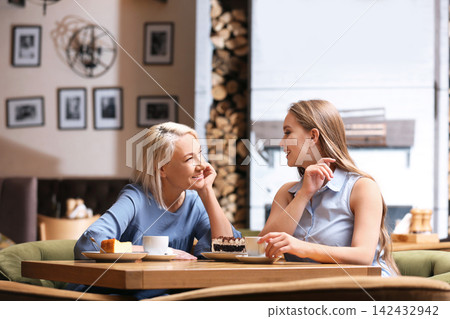 Mother and her adult daughter spending time together in cafe Mother and her adult daughter spending time together in cafe 142432942