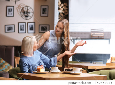 Mother and her adult daughter spending time together in cafe Mother and her adult daughter spending time together in cafe 142432943