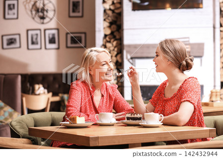 Mother and her adult daughter spending time together in cafe Mother and her adult daughter spending time together in cafe 142432944