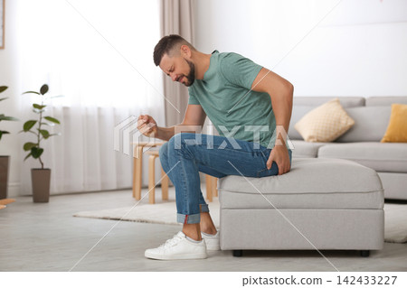 Man suffering from hemorrhoid in living room Man suffering from hemorrhoid in living room 142433227