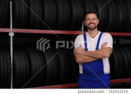 Male mechanic near rack with car tires in auto store Male mechanic near rack with car tires in auto store 142433234
