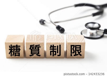 一塊標示「限制碳水化合物攝取」的方塊和一個聽診器。 一塊標示「限制碳水化合物攝取」的方塊和一個聽診器。 142433236