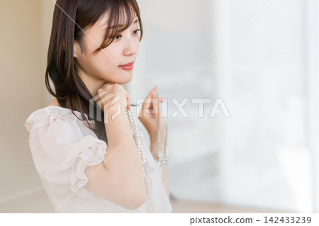 一位佩戴珍珠項鍊的年輕亞洲女性。 一位佩戴珍珠項鍊的年輕亞洲女性。 142433239