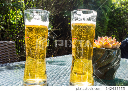 在倫敦郊區一家酒吧里,陽光明媚,桌子上擺著一杯裝在細長玻璃杯裡的泡沫豐富的啤酒。 在倫敦郊區一家酒吧里,陽光明媚,桌子上擺著一杯裝在細長玻璃杯裡的泡沫豐富的啤酒。 142433355