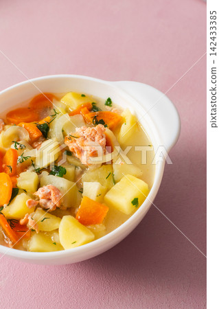 A bowl of red fish and potato soup is placed on a simple table. The soup has pieces of carrots and onions. It looks healthy and is suitable for breakfast or lunch A bowl of red fish and potato soup is placed on a simple table. The soup has pieces of carrots and onions. It looks healthy and is suitable for breakfast or lunch 142433385
