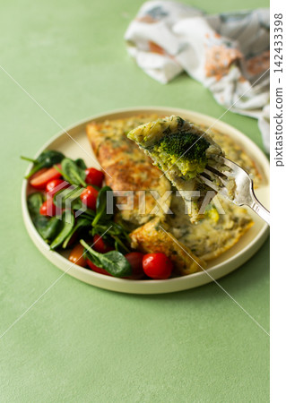 A plate holds a potato omelette made with eggs and filled with spinach and tomatoes. The meal looks fresh and healthy and is ideal for breakfast any day A plate holds a potato omelette made with eggs and filled with spinach and tomatoes. The meal looks fresh and healthy and is ideal for breakfast any day 142433398