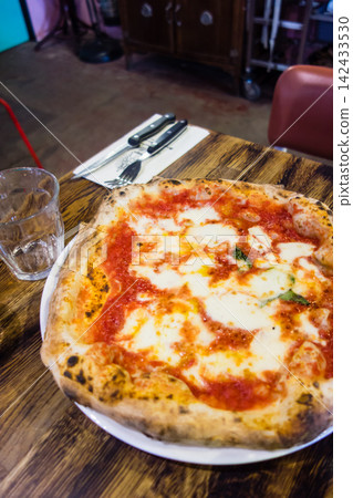 Authentic Italian cuisine: Pizza topped with tomatoes, cheese, and arugula, and a salad, at a restaurant in the suburbs of London. Authentic Italian cuisine: Pizza topped with tomatoes, cheese, and arugula, and a salad, at a restaurant in the suburbs of London. 142433530