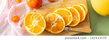 Citrus fruits are being prepared for Christmas drying. Different types of citrus are placed on a cutting board and drying rack in a home kitchen. The scene shows a festive activity, banner Citrus fruits are being prepared for Christmas drying. Different types of citrus are placed on a cutting board and drying rack in a home kitchen. The scene shows a festive activity, banner 142433579