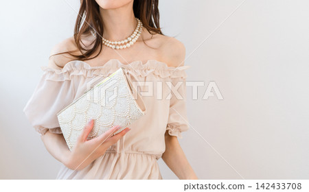 一位盛裝打扮的女士提著一個派對包 一位盛裝打扮的女士提著一個派對包 142433708
