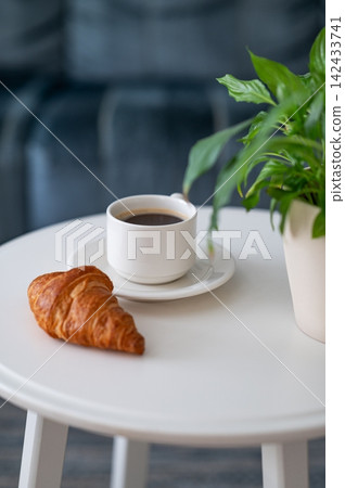 Coffee and Croissant on a Minimalist Table with Green Plant Coffee and Croissant on a Minimalist Table with Green Plant 142433741