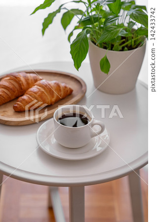 Coffee and Croissant on a Minimalist Table with Green Plant Coffee and Croissant on a Minimalist Table with Green Plant 142433742