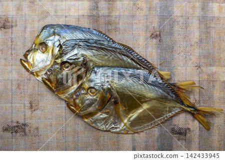 Three smoked sea fish close-up on a fabric background Three smoked sea fish close-up on a fabric background 142433945