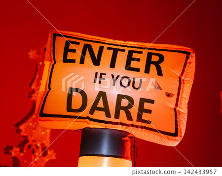 An illuminated Halloween sign invites visitors with a spooky message after dark. The glowing decoration creates a festive haunted house atmosphere for trick-or-treaters. An illuminated Halloween sign invites visitors with a spooky message after dark. The glowing decoration creates a festive haunted house atmosphere for trick-or-treaters. 142433957