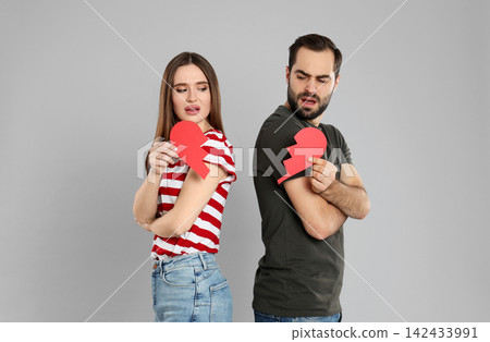 Couple with torn paper heart on grey background. Relationship problems Couple with torn paper heart on grey background. Relationship problems 142433991