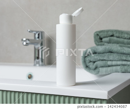 White flip top cosmetic bottle mockup near towel on green bathroom vanity. Cosmetic packaging White flip top cosmetic bottle mockup near towel on green bathroom vanity. Cosmetic packaging 142434087