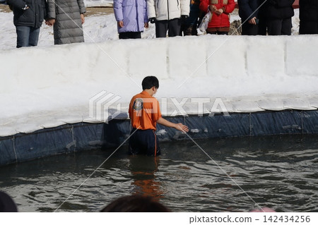 Boy in Water with Spectators at Winter Festival Boy in Water with Spectators at Winter Festival 142434256
