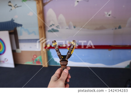 Hand Holding Traditional Bamboo Musical Instrument in Playroom 142434283