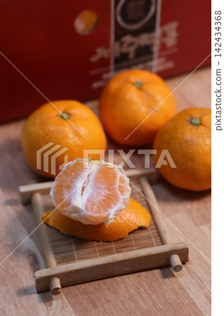 Fresh Peeled Oranges and Whole Citrus Fruits on Wooden Surface Fresh Peeled Oranges and Whole Citrus Fruits on Wooden Surface 142434368