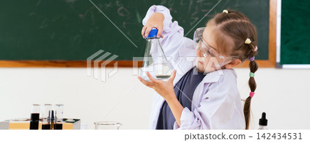 Little girl in lab coat holding a flask in a science classroom Little girl in lab coat holding a flask in a science classroom 142434531