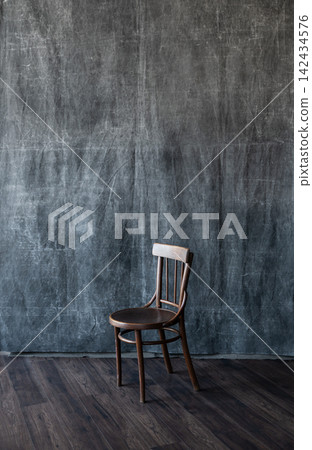 Vintage wooden chair standing alone against a dark textured canvas background in studio Vintage wooden chair standing alone against a dark textured canvas background in studio 142434576