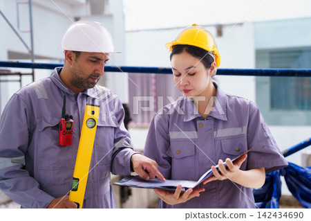 Diverse construction workers walking and reviewing plans at a building site Diverse construction workers walking and reviewing plans at a building site 142434690