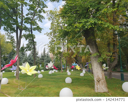 Creative art installation in a green city park featuring colorful giant decorative flowers Creative art installation in a green city park featuring colorful giant decorative flowers 142434771