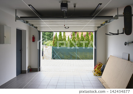 Open sectional garage door with automatic opener inside residential garage Open sectional garage door with automatic opener inside residential garage 142434877
