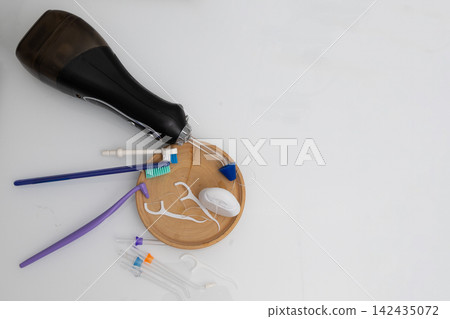 Flat lay of toothbrush, flossers, floss, and irrigator on wooden tray for daily dental care Flat lay of toothbrush, flossers, floss, and irrigator on wooden tray for daily dental care 142435072