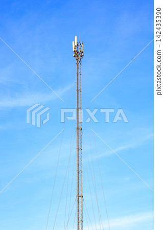Tall Guyed Lattice Cellular Tower with Transmitters on Blue Sky Background Tall Guyed Lattice Cellular Tower with Transmitters on Blue Sky Background 142435390