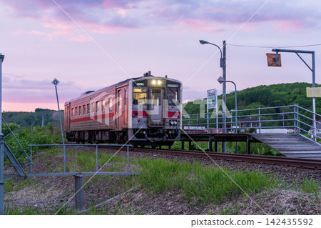 黃昏時分,一輛柴油動車組列車停靠在宗谷本線的日新站。 黃昏時分,一輛柴油動車組列車停靠在宗谷本線的日新站。 142435592
