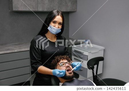 Dentist checking patient teeth during oral examination Dentist checking patient teeth during oral examination 142435611